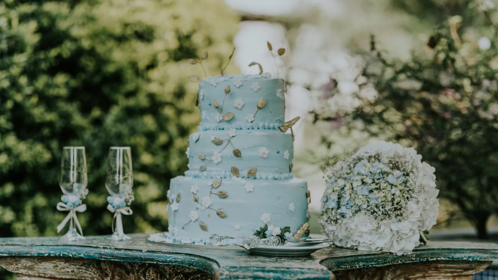 Beautiful blue wedding cake with floral decor and a bouquet, perfect for a romantic setting.